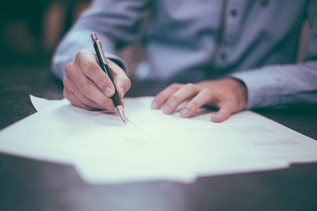 Person writing on a stack of papers